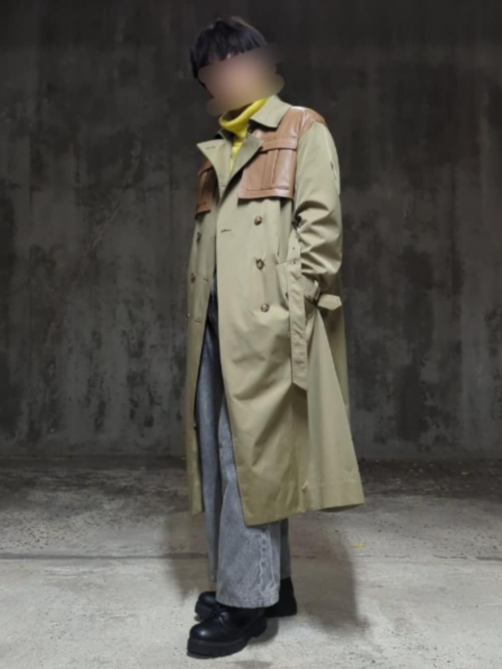 グリーン系のトレンチコート、イエロー系のニット/セーター、グレー系のデニムパンツを着用したメンズの冬コーディネートの2枚目の写真