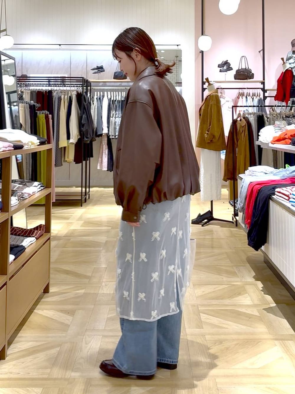 ホワイト系のショルダーバッグ、ブルー系のデニムパンツ、ブラウン系のブルゾンを着用したレディースの春コーディネートの3枚目の写真