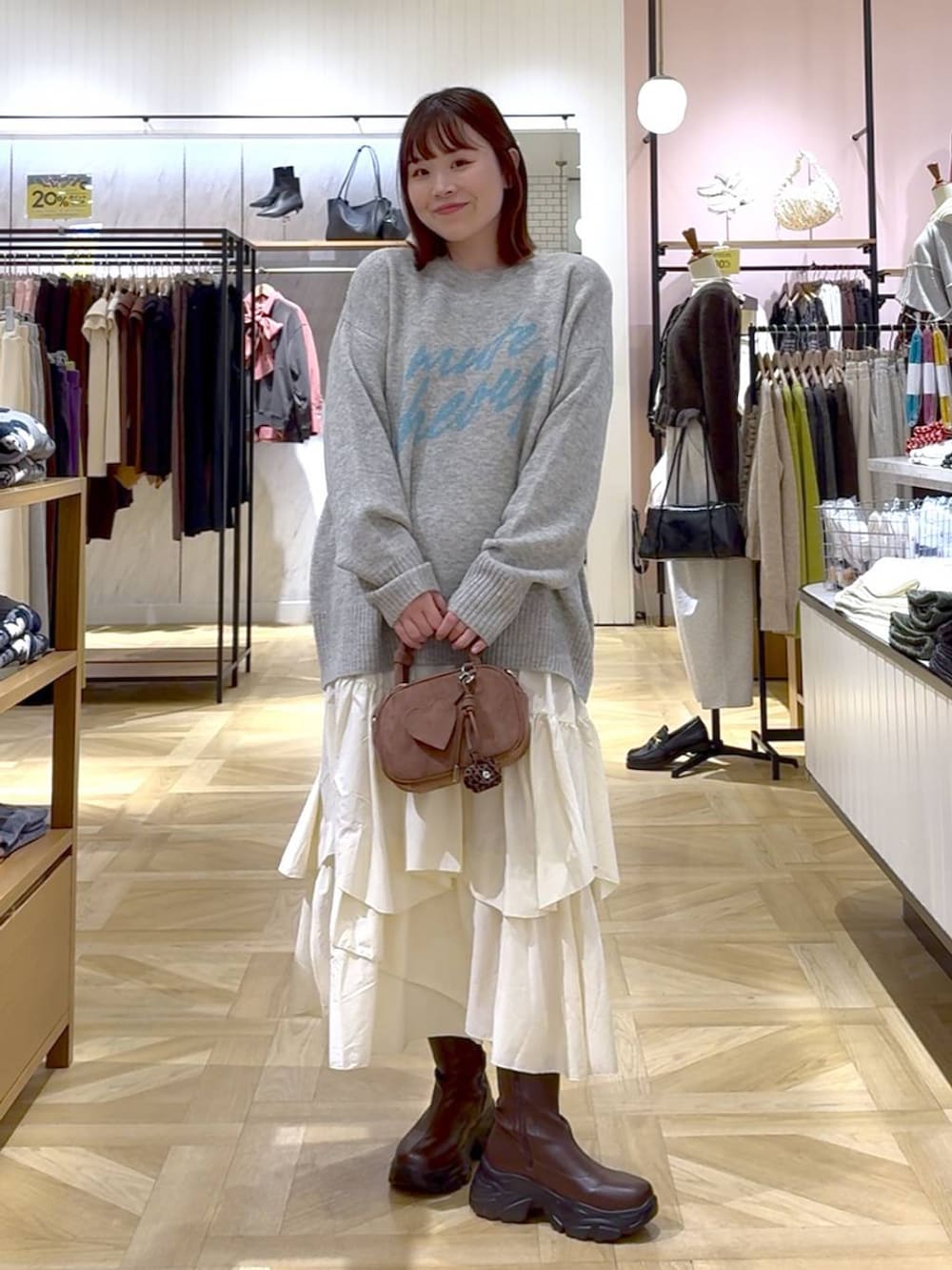 ブラウン系のブーツ、ホワイト系のスカート、ブラウン系のブルゾンを着用したレディースの秋コーディネートの4枚目の写真