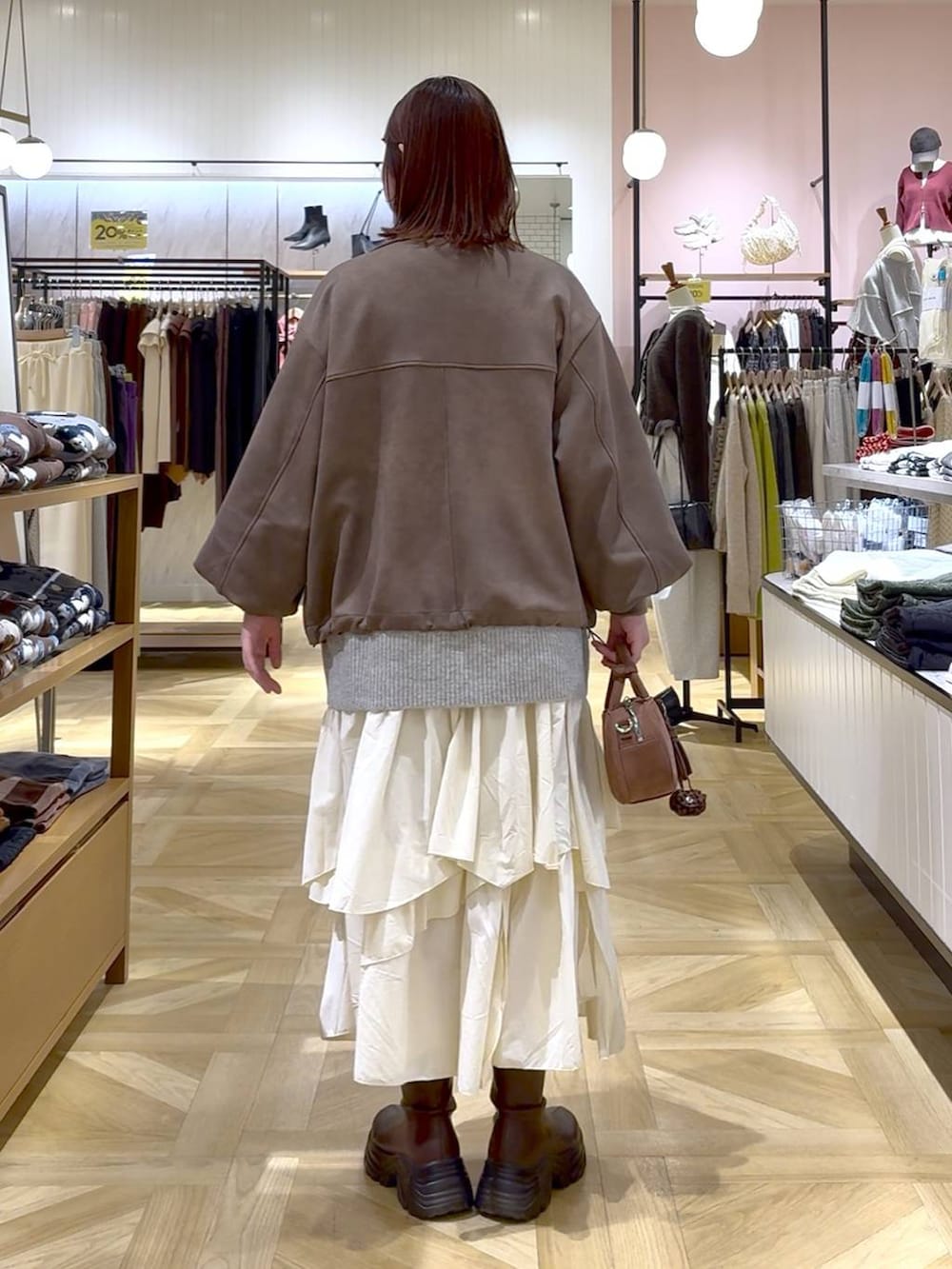 ブラウン系のブーツ、ホワイト系のスカート、ブラウン系のブルゾンを着用したレディースの秋コーディネートの3枚目の写真