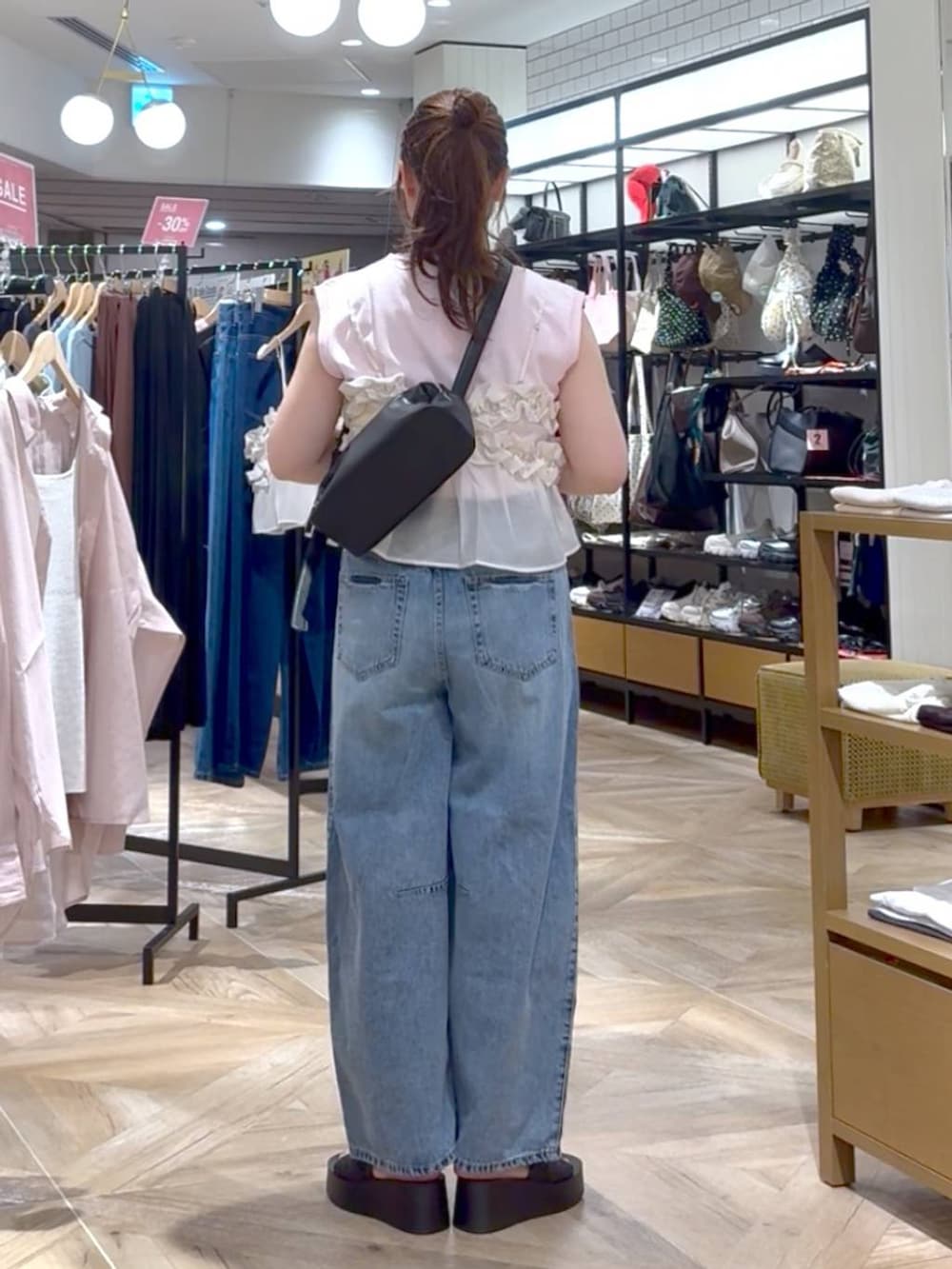 ホワイト系のキャミソール、ブラック系のサンダル、ブルー系のデニムパンツを着用したレディースの夏コーディネートの3枚目の写真