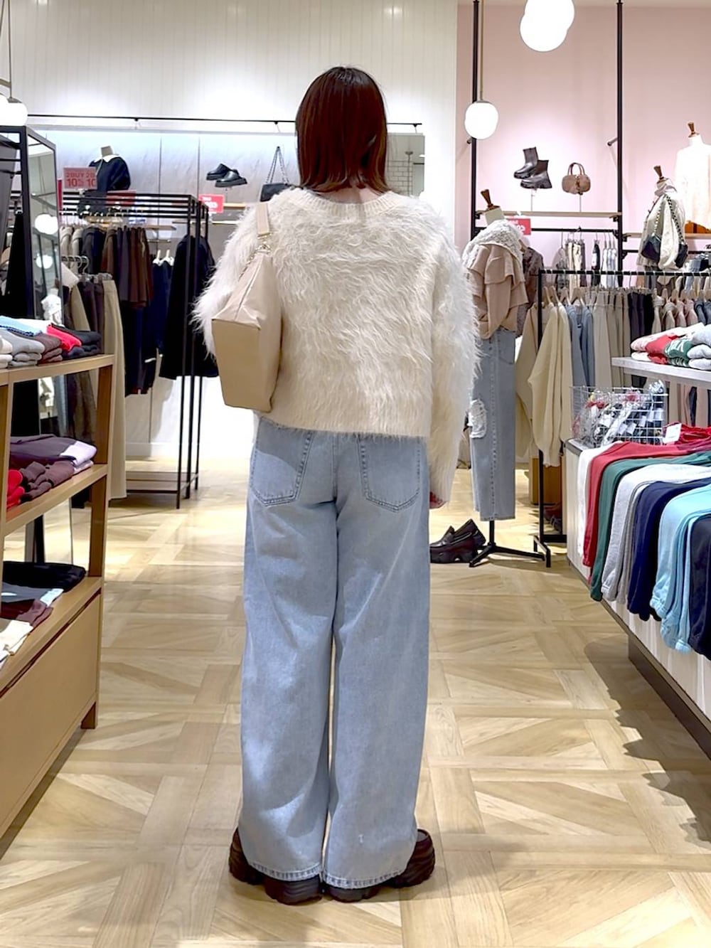 ブルー系のデニムパンツ、ホワイト系のカーディガン/ボレロ、ベージュ系のショルダーバッグを着用したレディースの冬コーディネートの2枚目の写真