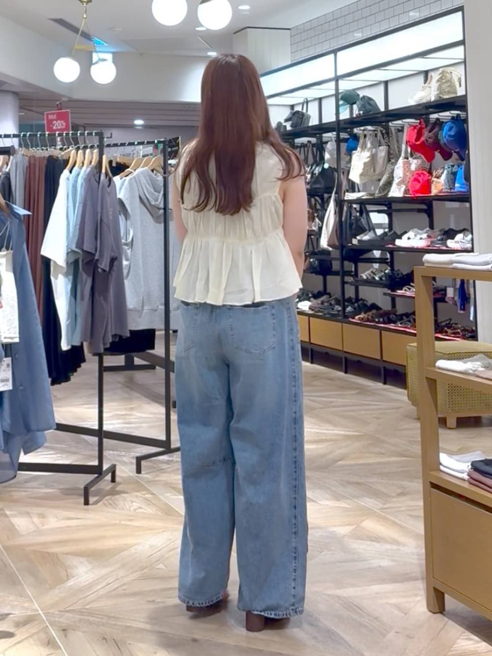 ブラウン系のタンクトップ、その他のトートバッグ、ブルー系のデニムパンツを着用したレディースの夏コーディネートの3枚目の写真