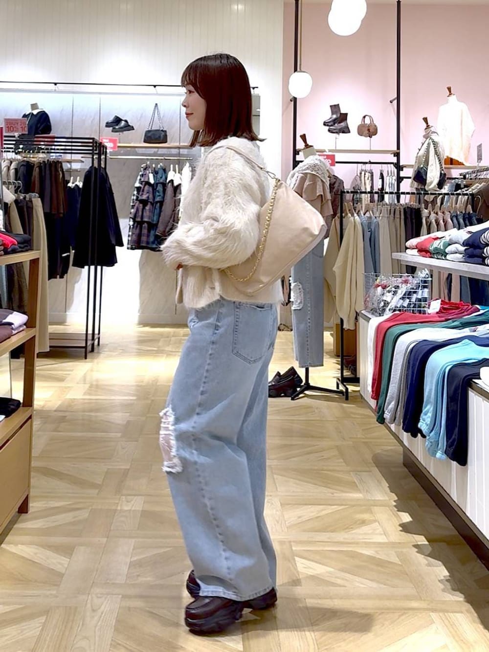 ブルー系のデニムパンツ、ホワイト系のカーディガン/ボレロ、ベージュ系のショルダーバッグを着用したレディースの冬コーディネートの3枚目の写真