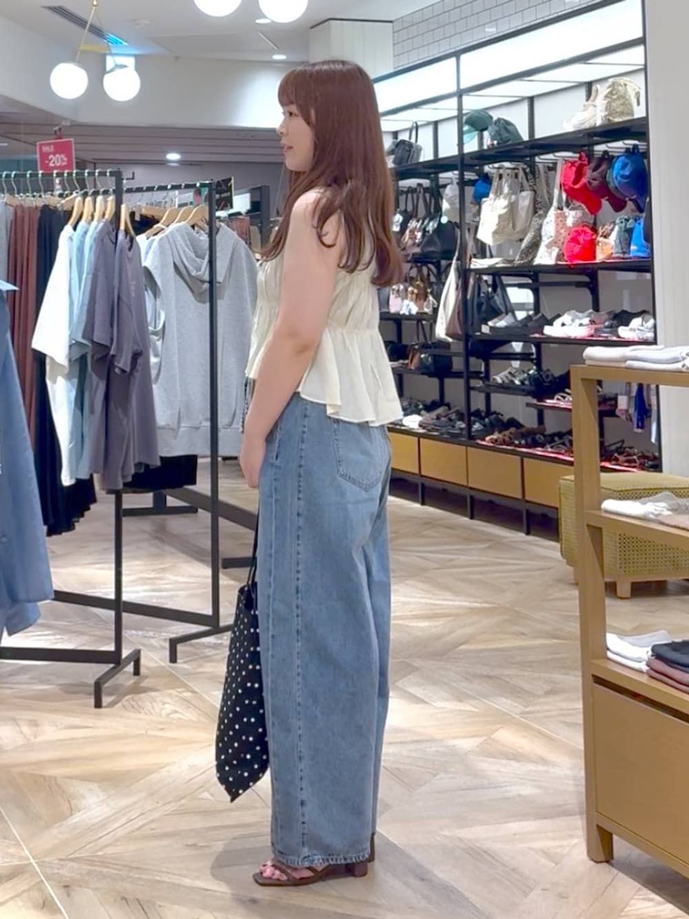 ブラウン系のタンクトップ、その他のトートバッグ、ブルー系のデニムパンツを着用したレディースの夏コーディネートの2枚目の写真