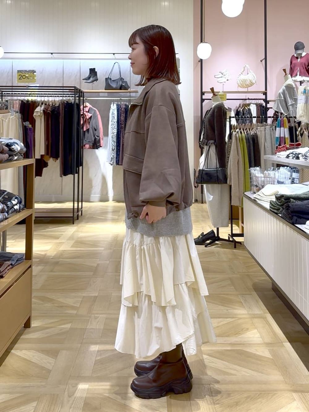 ブラウン系のブーツ、ホワイト系のスカート、ブラウン系のブルゾンを着用したレディースの秋コーディネートの2枚目の写真