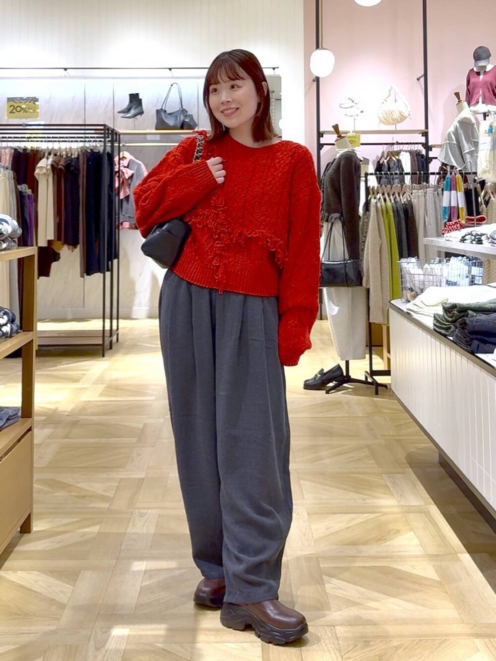 グレー系のその他パンツ、レッド系のポロシャツ、ブラック系のショルダーバッグを着用したレディースの秋コーディネートの4枚目の写真