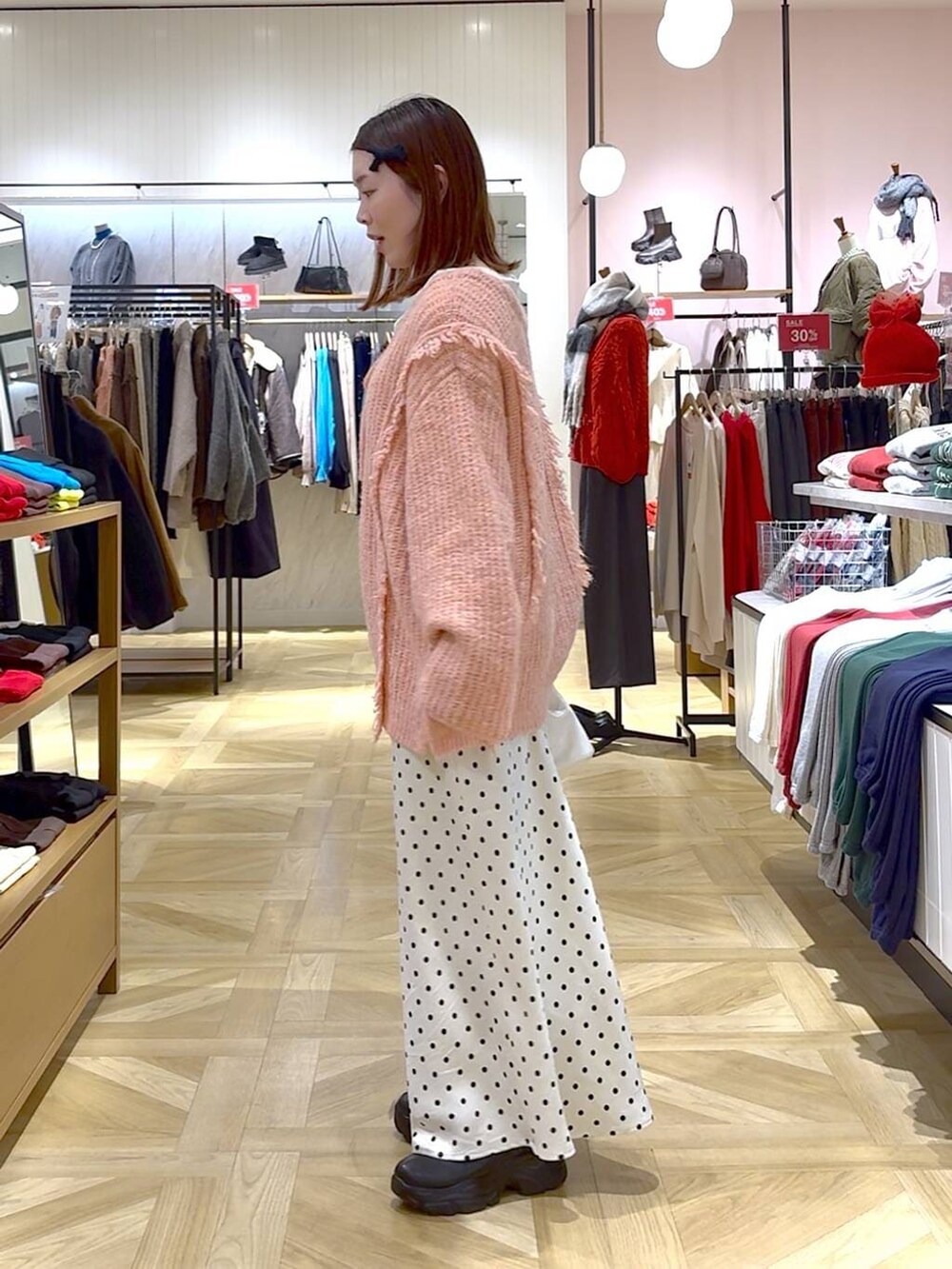 ピンク系のニット/セーター、ブラック系のブーツ、ホワイト系のスカートを着用したレディースの冬コーディネートの2枚目の写真