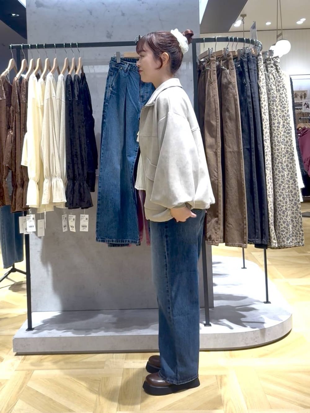 ブルー系のデニムパンツ、ブラウン系のサンダル、ホワイト系のブルゾンを着用したレディースの秋コーディネートの2枚目の写真
