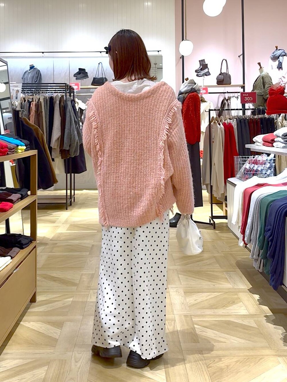 ピンク系のニット/セーター、ブラック系のブーツ、ホワイト系のスカートを着用したレディースの冬コーディネートの3枚目の写真