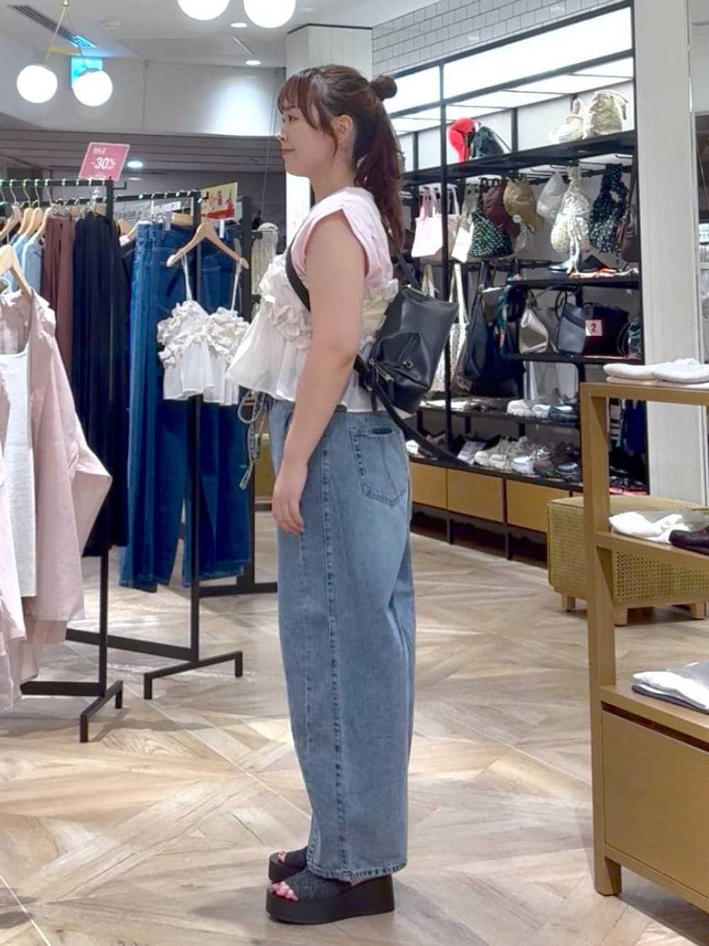 ホワイト系のキャミソール、ブラック系のサンダル、ブルー系のデニムパンツを着用したレディースの夏コーディネートの2枚目の写真