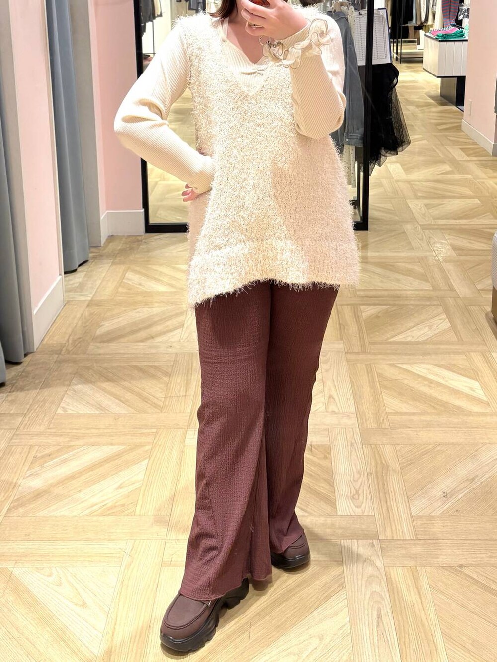 ブラウン系のローファー、ホワイト系のニット/セーター、ホワイト系のベストを着用したレディースの冬コーディネートの4枚目の写真
