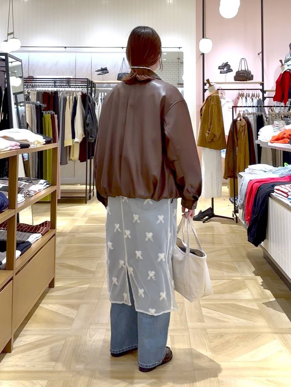 ホワイト系のショルダーバッグ、ブルー系のデニムパンツ、ブラウン系のブルゾンを着用したレディースの春コーディネートの2枚目の写真