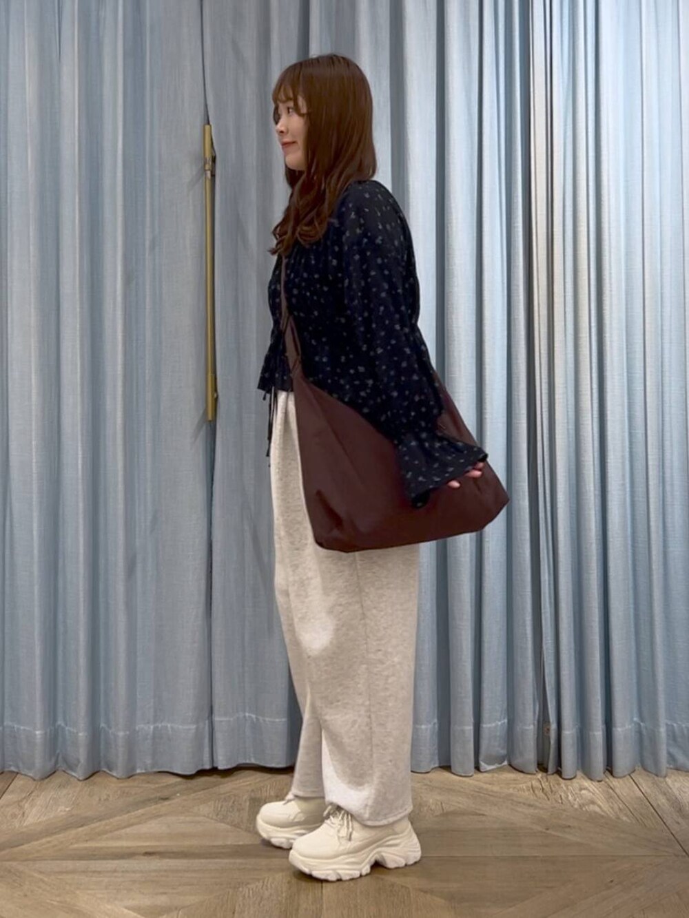 ブラウン系のショルダーバッグ、ホワイト系のスニーカー、グレー系のスウェットパンツを着用したレディースの春コーディネートの2枚目の写真