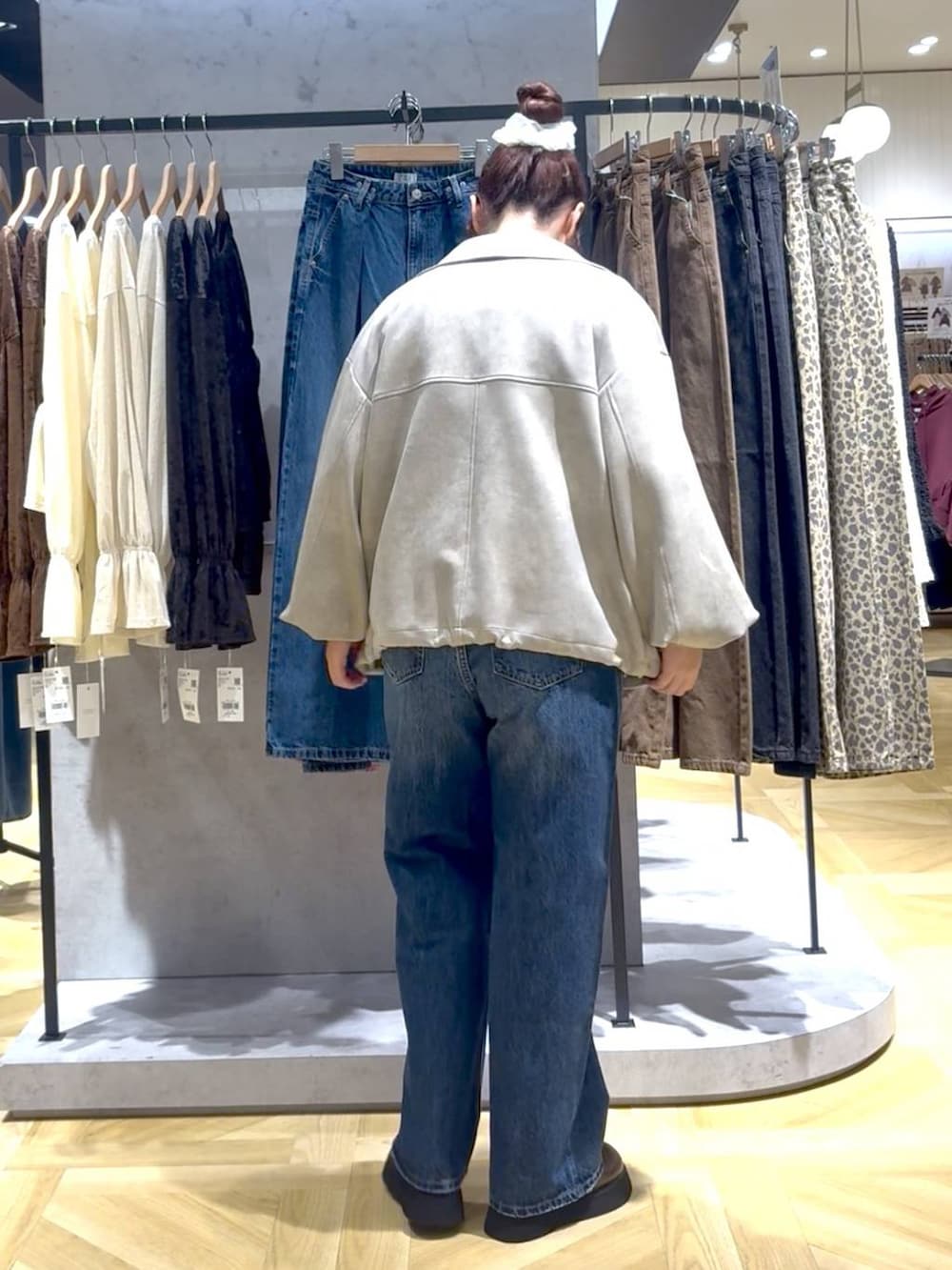 ブルー系のデニムパンツ、ブラウン系のサンダル、ホワイト系のブルゾンを着用したレディースの秋コーディネートの3枚目の写真