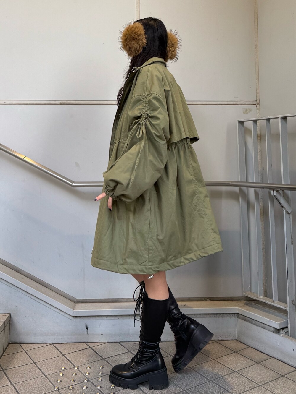 ブラック系のブーツ、グリーン系のモッズコート、ベージュ系のイヤーマフを着用したレディースの秋コーディネートの2枚目の写真