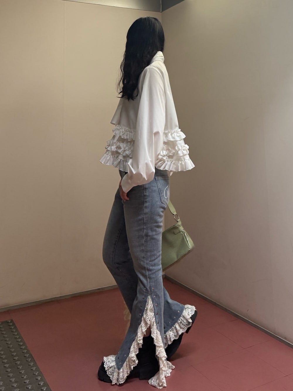 グリーン系のハンドバッグ、ホワイト系のシャツ/ブラウス、ブルー系のデニムパンツを着用したレディースの冬コーディネートの3枚目の写真