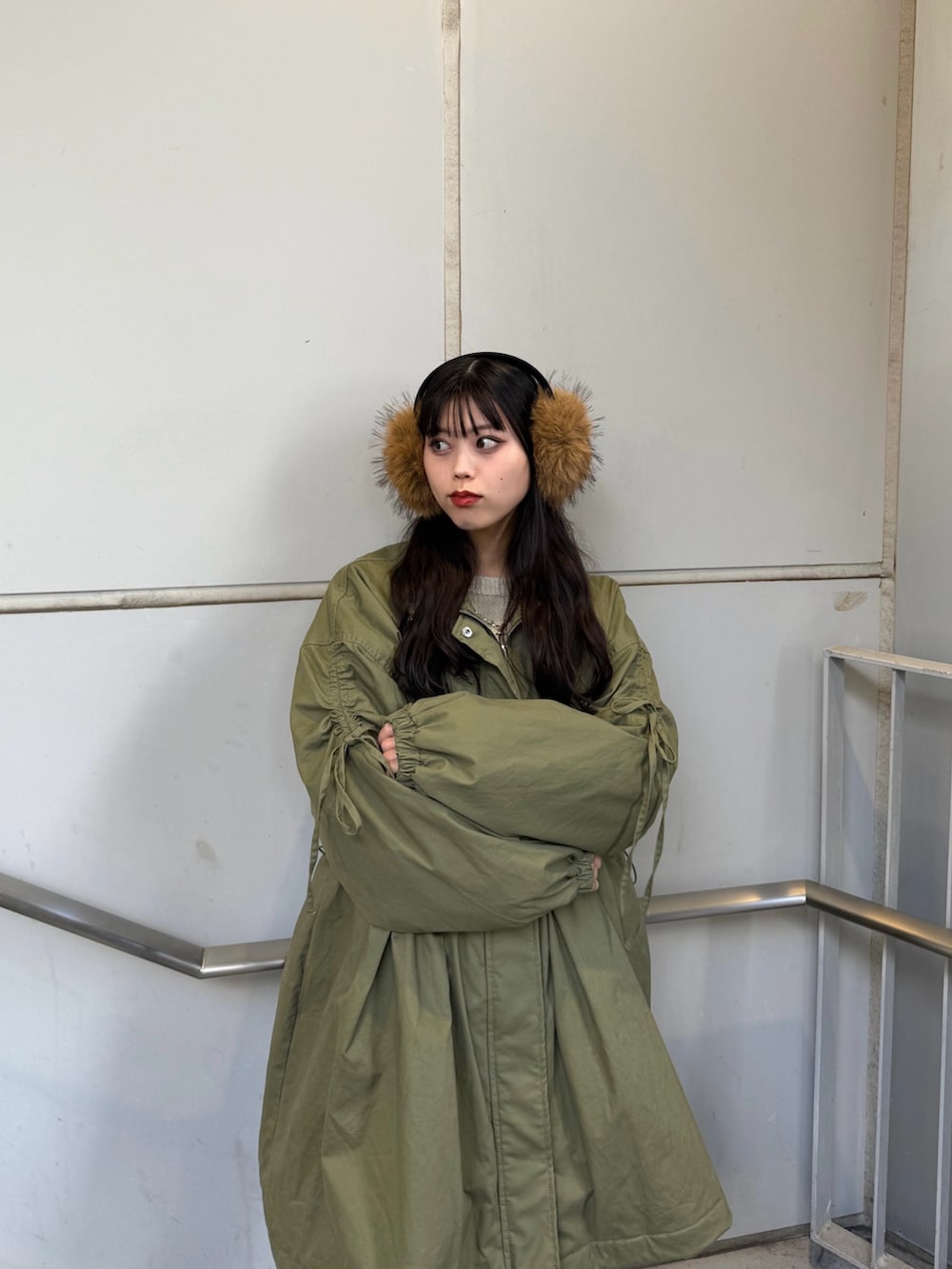 ブラック系のブーツ、グリーン系のモッズコート、ベージュ系のイヤーマフを着用したレディースの秋コーディネートの4枚目の写真