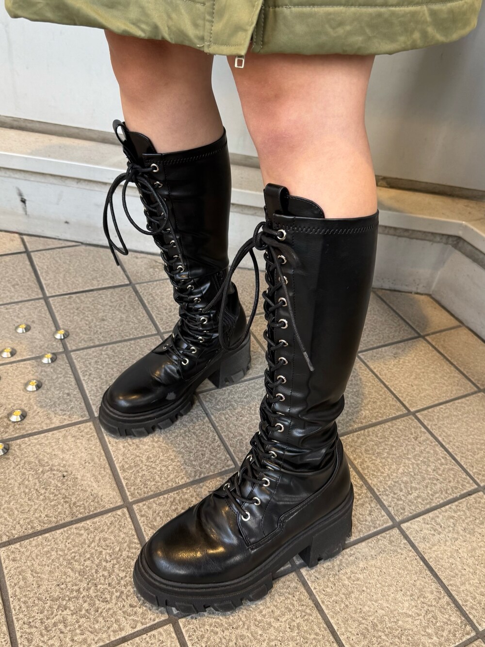 ブラック系のブーツ、グリーン系のモッズコート、ベージュ系のイヤーマフを着用したレディースの秋コーディネートの9枚目の写真