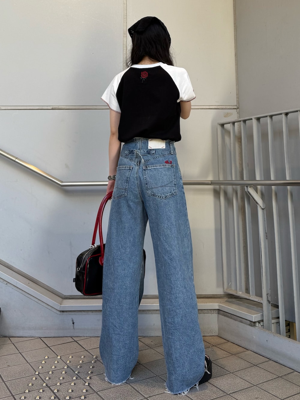 ブラック系のボストンバッグ、ブルー系のデニムパンツ、ブラック系のTシャツ/カットソーを着用したレディースの夏コーディネートの3枚目の写真