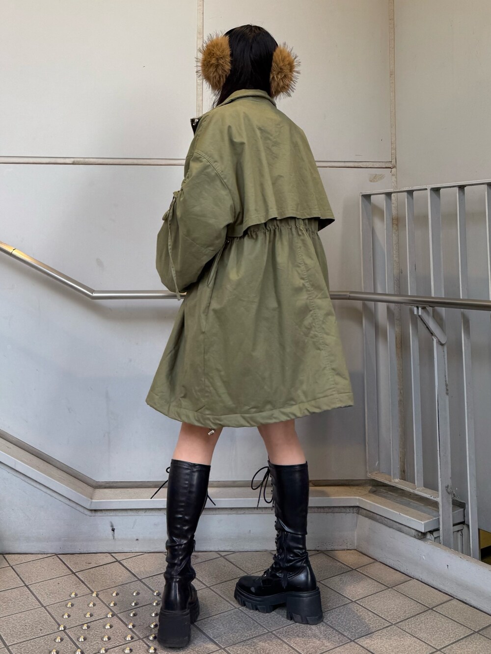 ブラック系のブーツ、グリーン系のモッズコート、ベージュ系のイヤーマフを着用したレディースの秋コーディネートの3枚目の写真