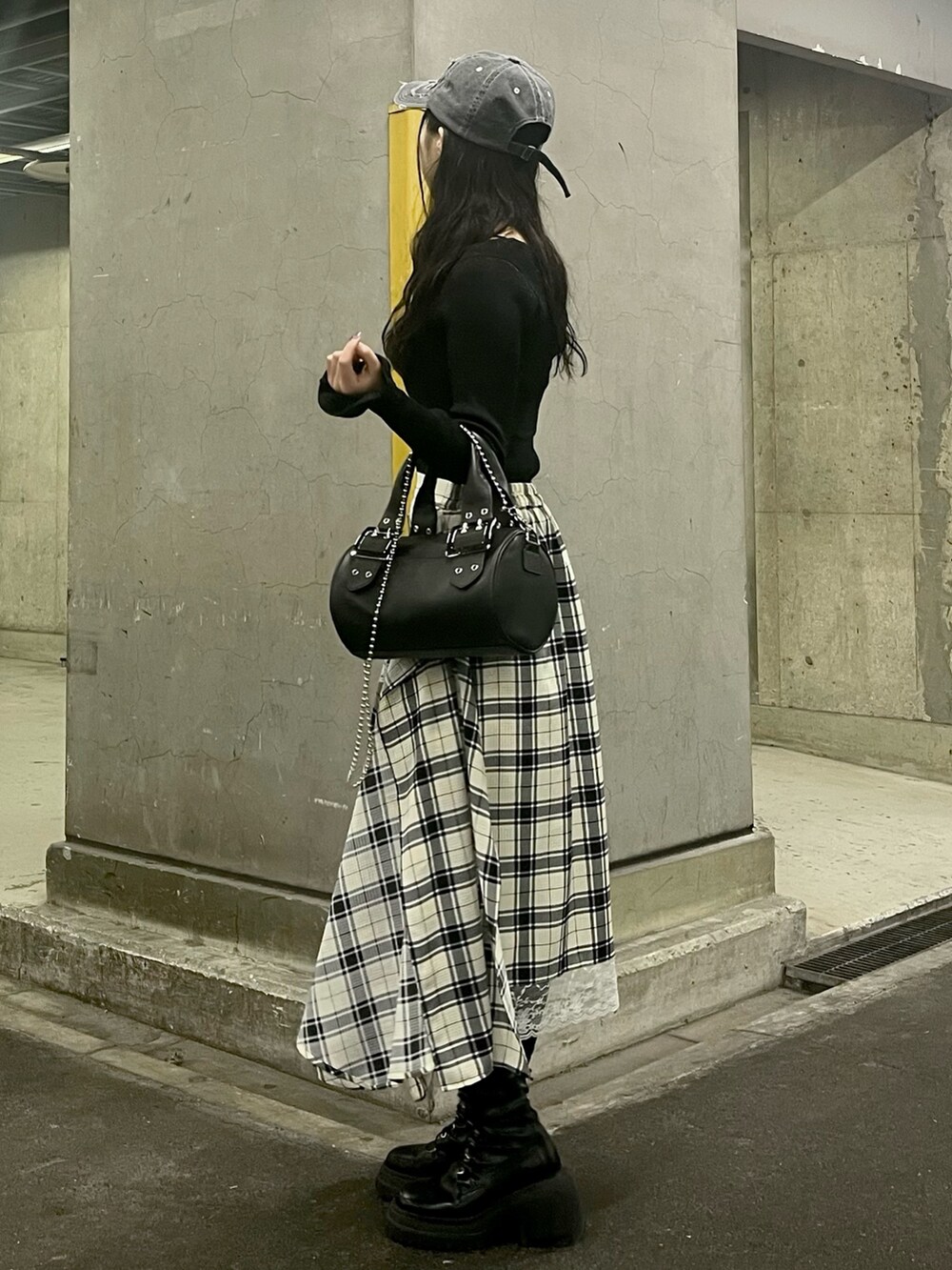 ブラック系のアンサンブル、ブラック系のボストンバッグ、ホワイト系のスカートを着用したレディースの春コーディネートの2枚目の写真