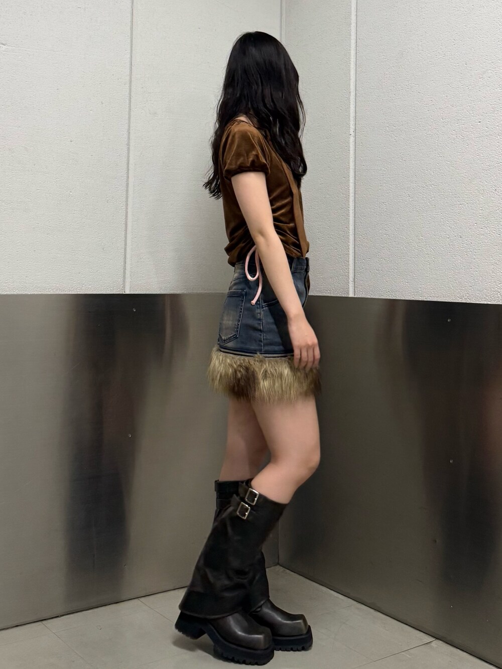 ブラウン系のTシャツ/カットソー、ブラック系のブーツ、ブルー系のスカートを着用したレディースの秋コーディネートの3枚目の写真