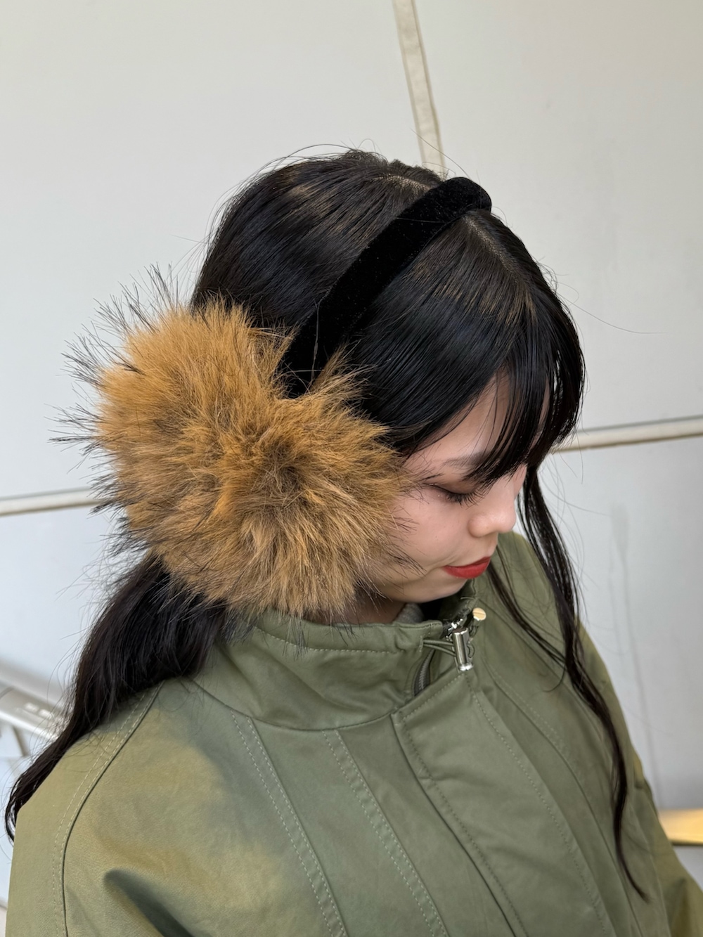 ブラック系のブーツ、グリーン系のモッズコート、ベージュ系のイヤーマフを着用したレディースの秋コーディネートの10枚目の写真