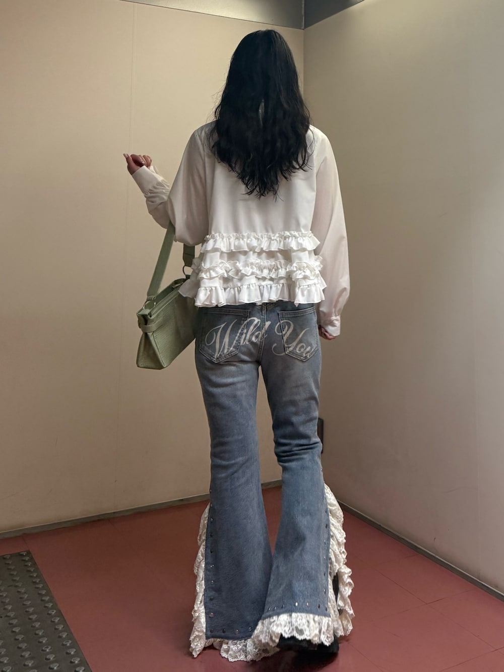 グリーン系のハンドバッグ、ホワイト系のシャツ/ブラウス、ブルー系のデニムパンツを着用したレディースの冬コーディネートの4枚目の写真