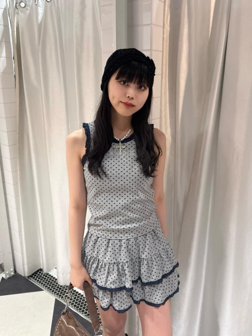 グレー系のタンクトップ、グレー系のスカート、ブラウン系のハンドバッグを着用したレディースの夏コーディネートの4枚目の写真