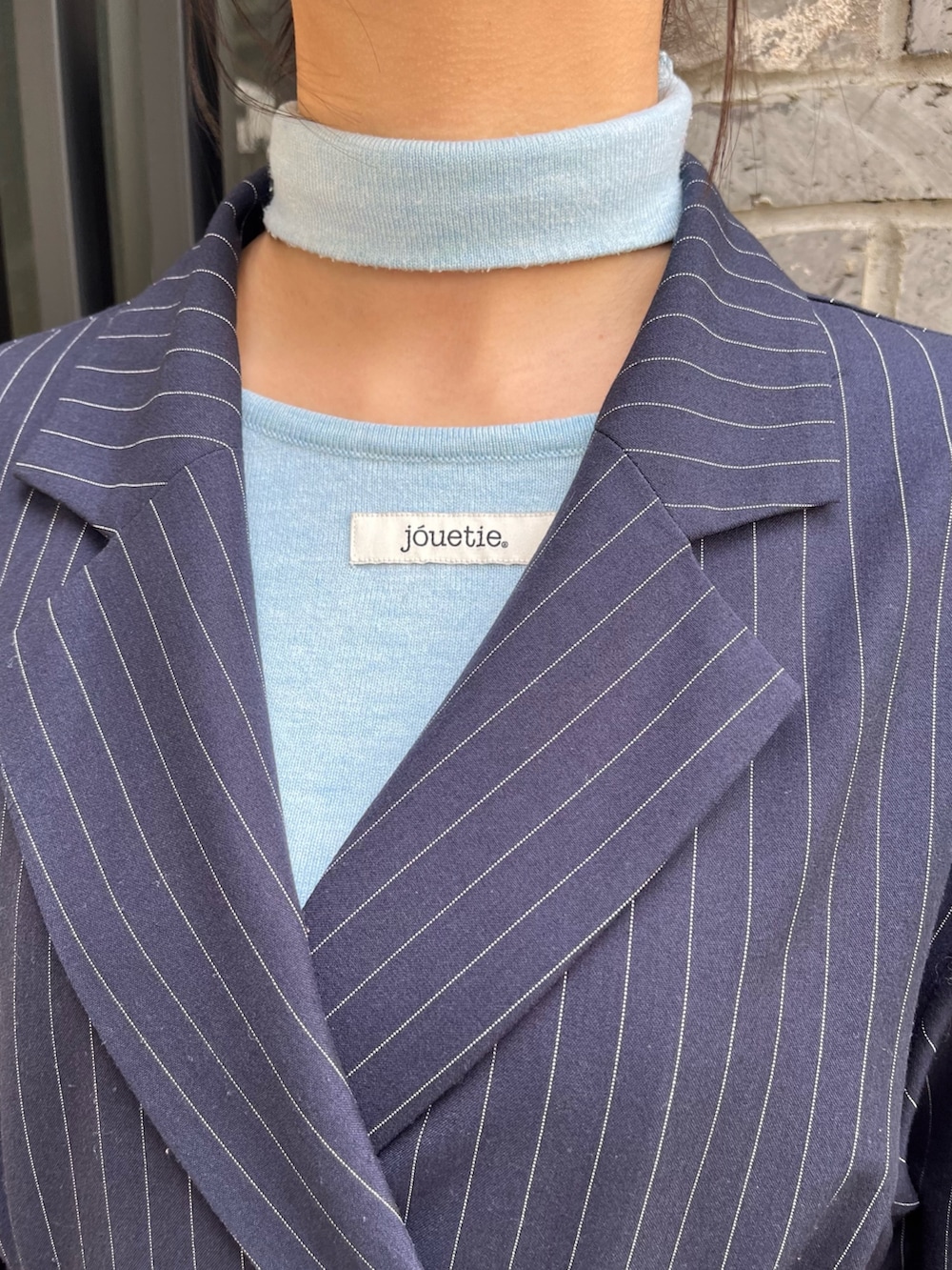 ブルー系のニット/セーター、ブルー系のテーラードジャケット、ブラック系のブーツを着用したレディースの冬コーディネートの5枚目の写真