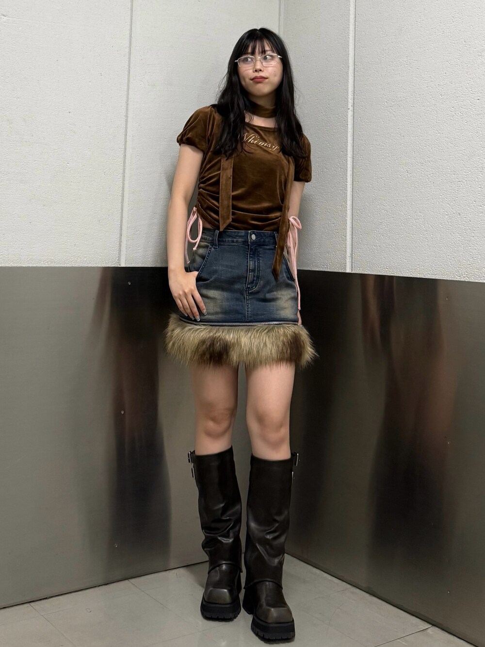 ブラウン系のTシャツ/カットソー、ブラック系のブーツ、ブルー系のスカートを着用したレディースの秋コーディネートの2枚目の写真