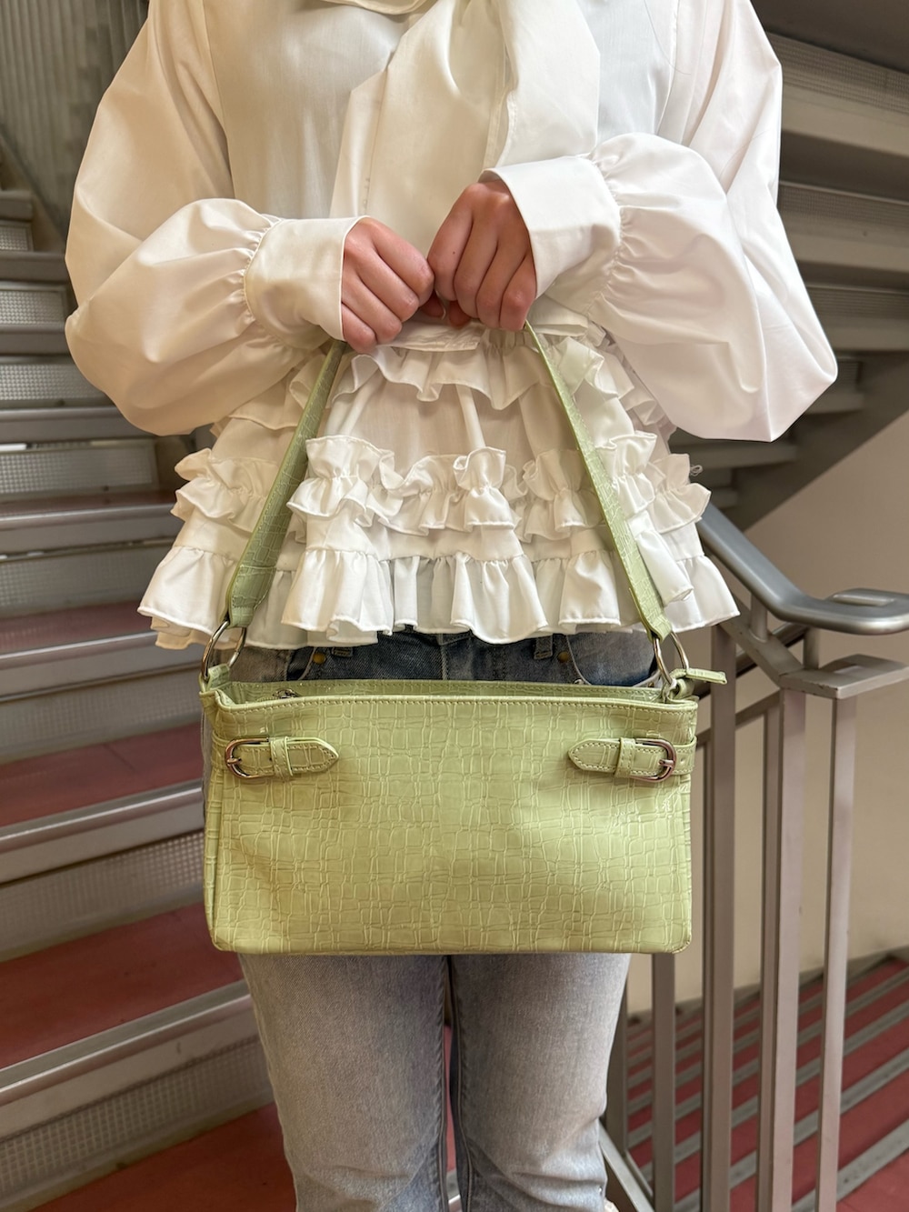 グリーン系のハンドバッグ、ホワイト系のシャツ/ブラウス、ブルー系のデニムパンツを着用したレディースの冬コーディネートの8枚目の写真