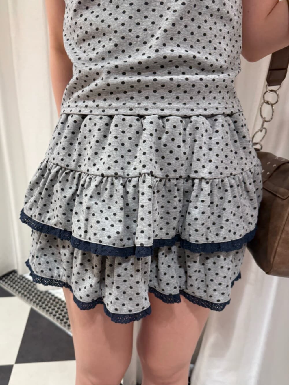 グレー系のタンクトップ、グレー系のスカート、ブラウン系のハンドバッグを着用したレディースの夏コーディネートの6枚目の写真