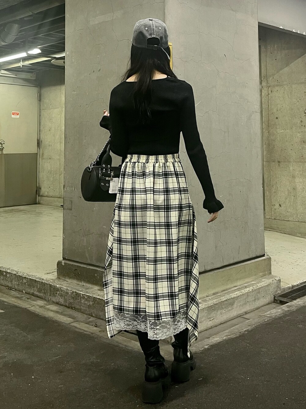 ブラック系のアンサンブル、ブラック系のボストンバッグ、ホワイト系のスカートを着用したレディースの春コーディネートの3枚目の写真