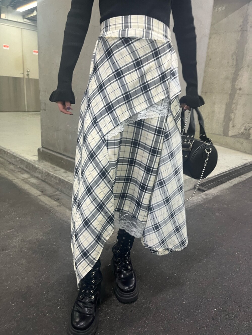 ブラック系のアンサンブル、ブラック系のボストンバッグ、ホワイト系のスカートを着用したレディースの春コーディネートの5枚目の写真