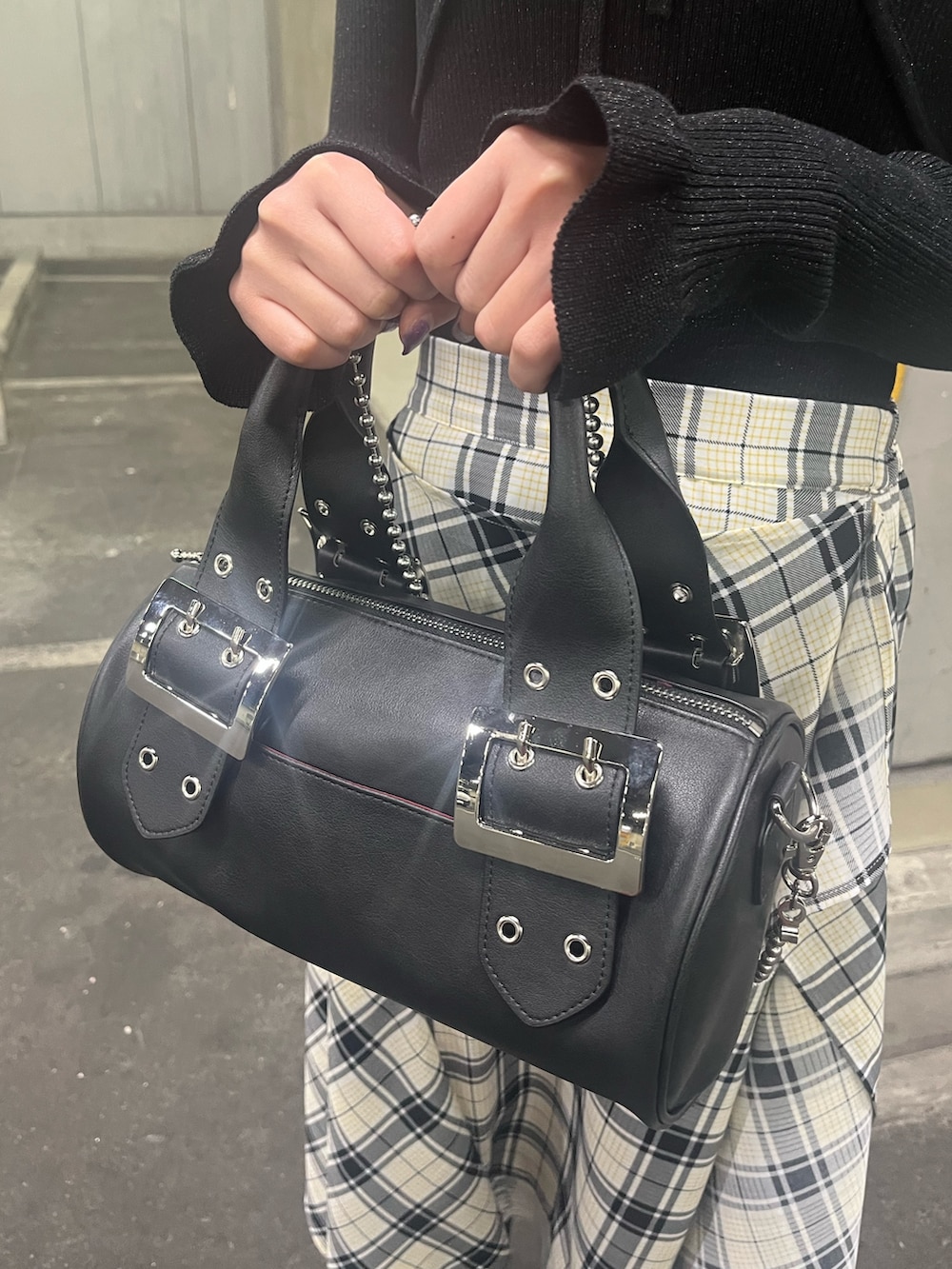 ブラック系のアンサンブル、ブラック系のボストンバッグ、ホワイト系のスカートを着用したレディースの春コーディネートの6枚目の写真