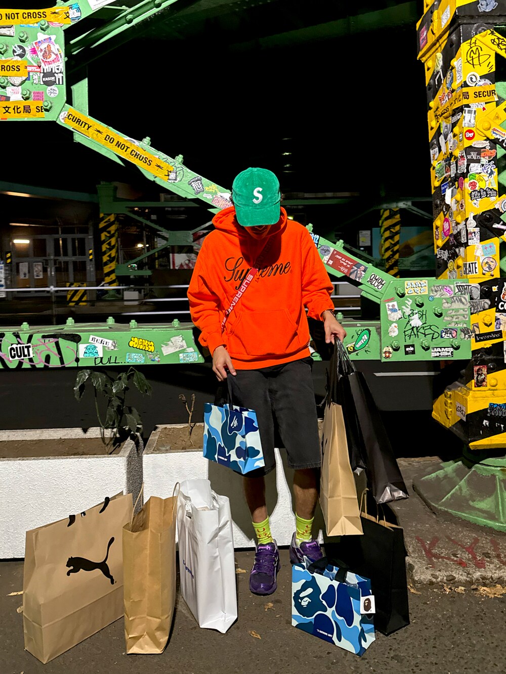 オレンジ系のスウェット、レッド系のショルダーバッグ、パープル系のスニーカーを着用したメンズの秋コーディネートの3枚目の写真