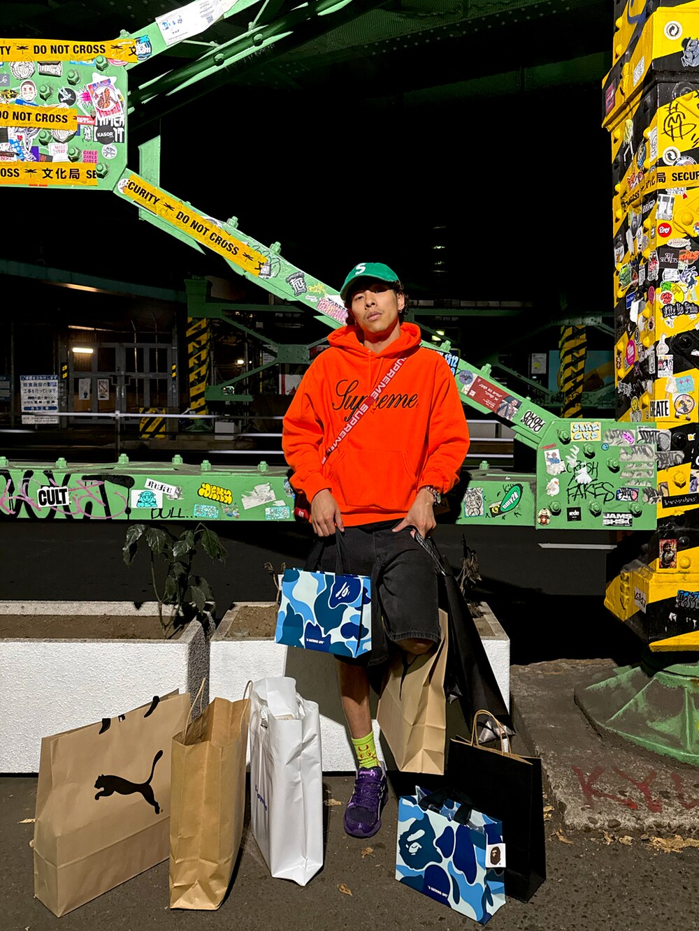 オレンジ系のスウェット、レッド系のショルダーバッグ、パープル系のスニーカーを着用したメンズの秋コーディネートの2枚目の写真