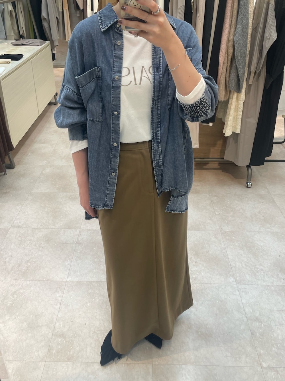 ブルー系のシャツ/ブラウス、ホワイト系のTシャツ/カットソー、ブラウン系のスカートを着用したレディースの秋コーディネートの3枚目の写真