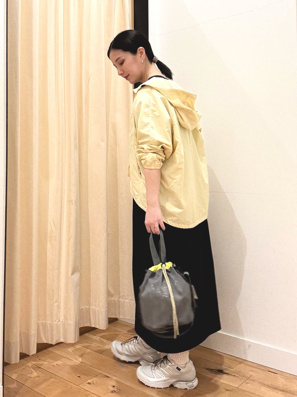 シルバー系のスニーカー、イエロー系のナイロンジャケット、ブラック系のワンピースを着用したレディースの春コーディネートの2枚目の写真