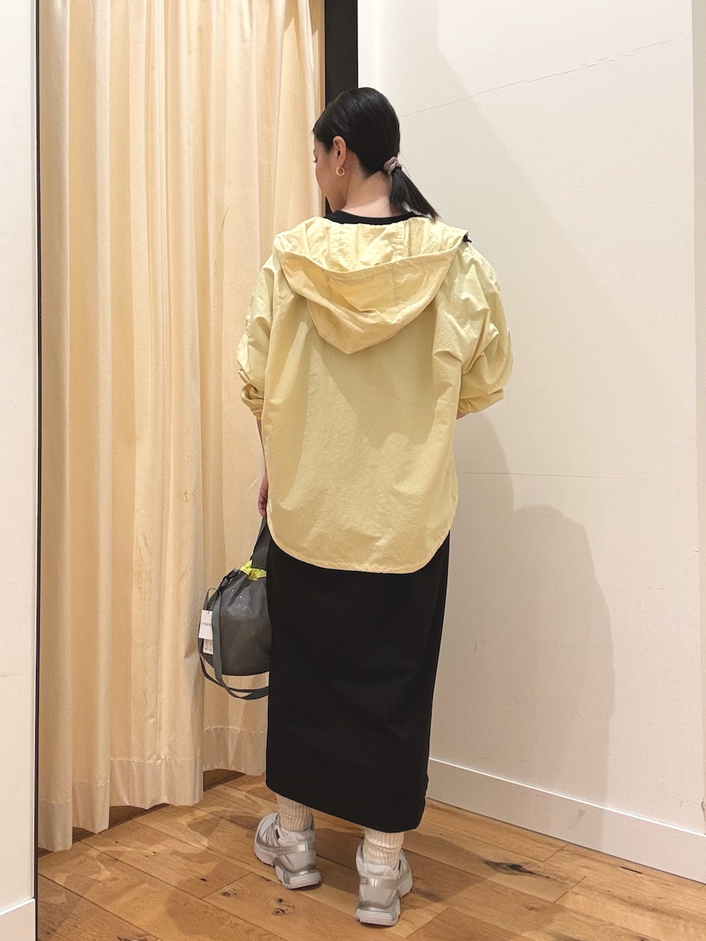 シルバー系のスニーカー、イエロー系のナイロンジャケット、ブラック系のワンピースを着用したレディースの春コーディネートの3枚目の写真