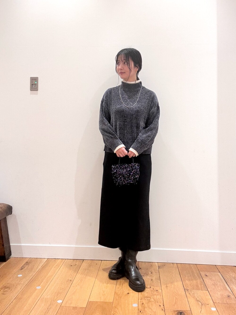 ホワイト系のダウンジャケット/コート、グレー系のニット/セーター、ブラック系のスカートを着用したレディースの秋コーディネートの4枚目の写真