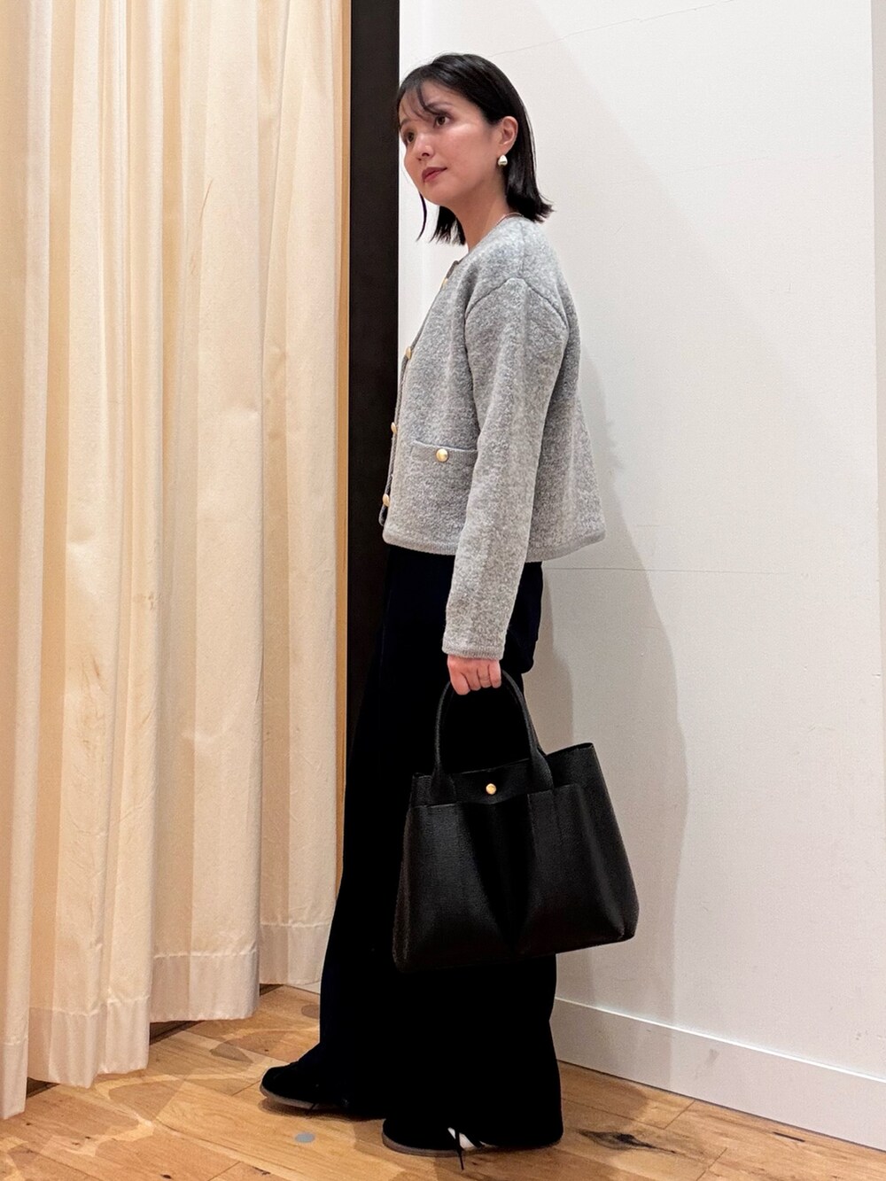 グレー系のカーディガン/ボレロ、ブルー系のデニムパンツ、ブラック系のトートバッグを着用したレディースの秋コーディネートの3枚目の写真