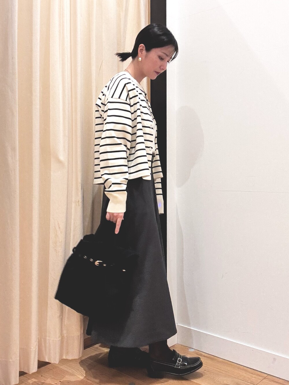 ホワイト系のTシャツ/カットソー、グレー系のスカート、ホワイト系のカーディガン/ボレロを着用したレディースの秋コーディネートの2枚目の写真