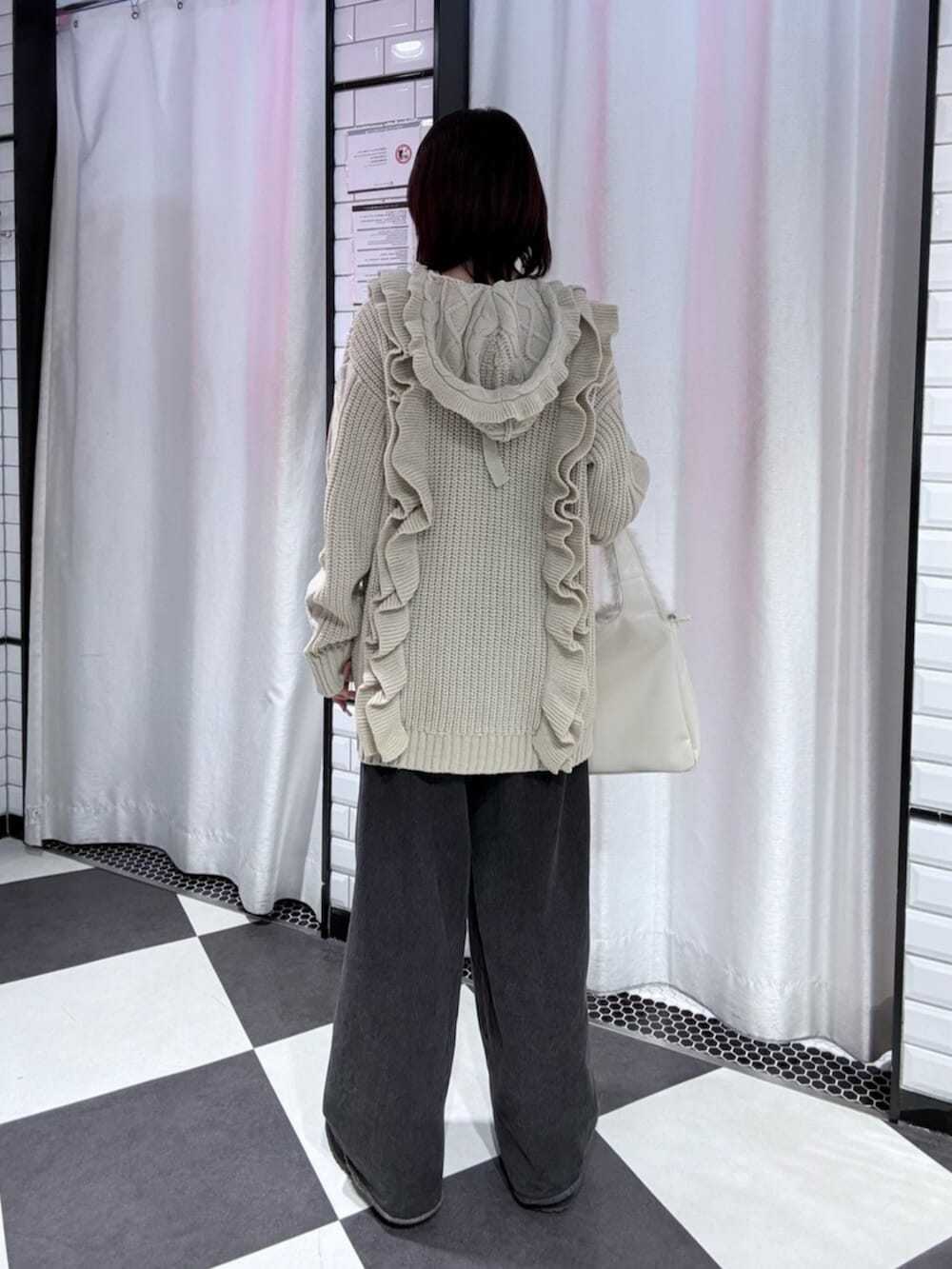 ブラック系のデニムパンツ、ホワイト系のニット/セーター、ホワイト系のハンドバッグを着用したレディースの冬コーディネートの3枚目の写真