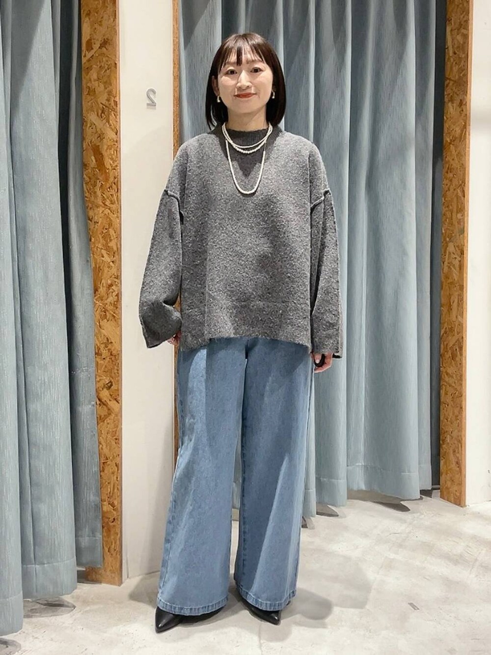 ブラック系のパンプス、グレー系のニット/セーター、ブルー系のデニムパンツを着用したレディースの冬コーディネートの7枚目の写真