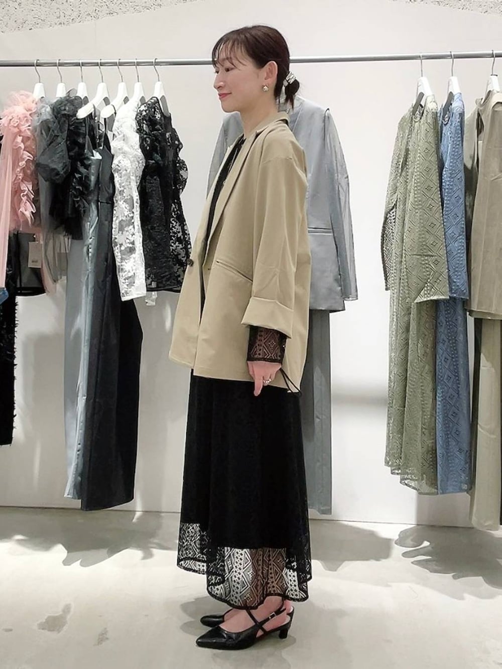 ベージュ系のテーラードジャケット、ブラック系のドレス、ゴールド系のネックレスを着用したレディースの春コーディネートの5枚目の写真