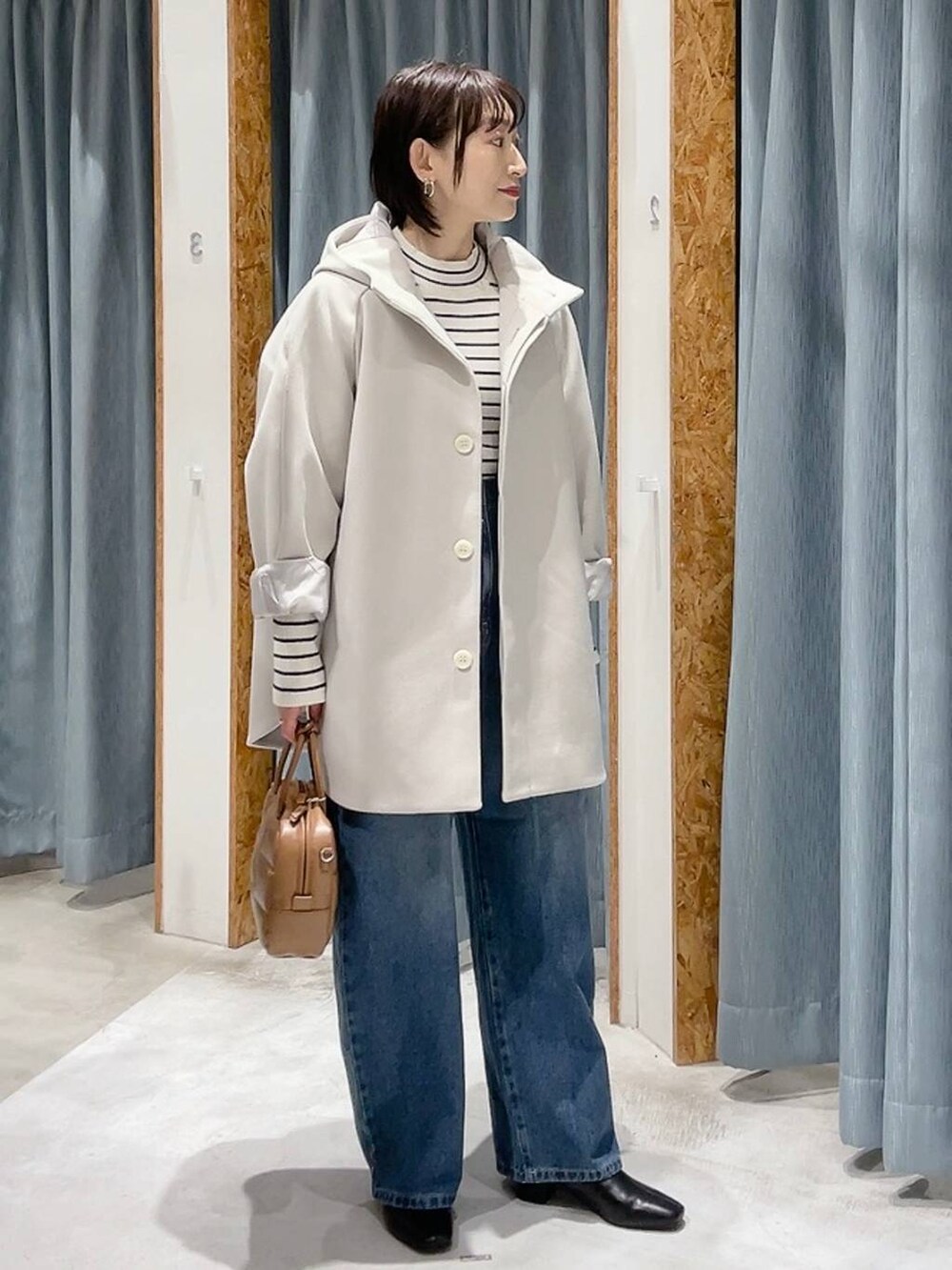 ホワイト系のポンチョ、ホワイト系のニット/セーター、ブルー系のデニムパンツを着用したレディースの秋コーディネートの3枚目の写真