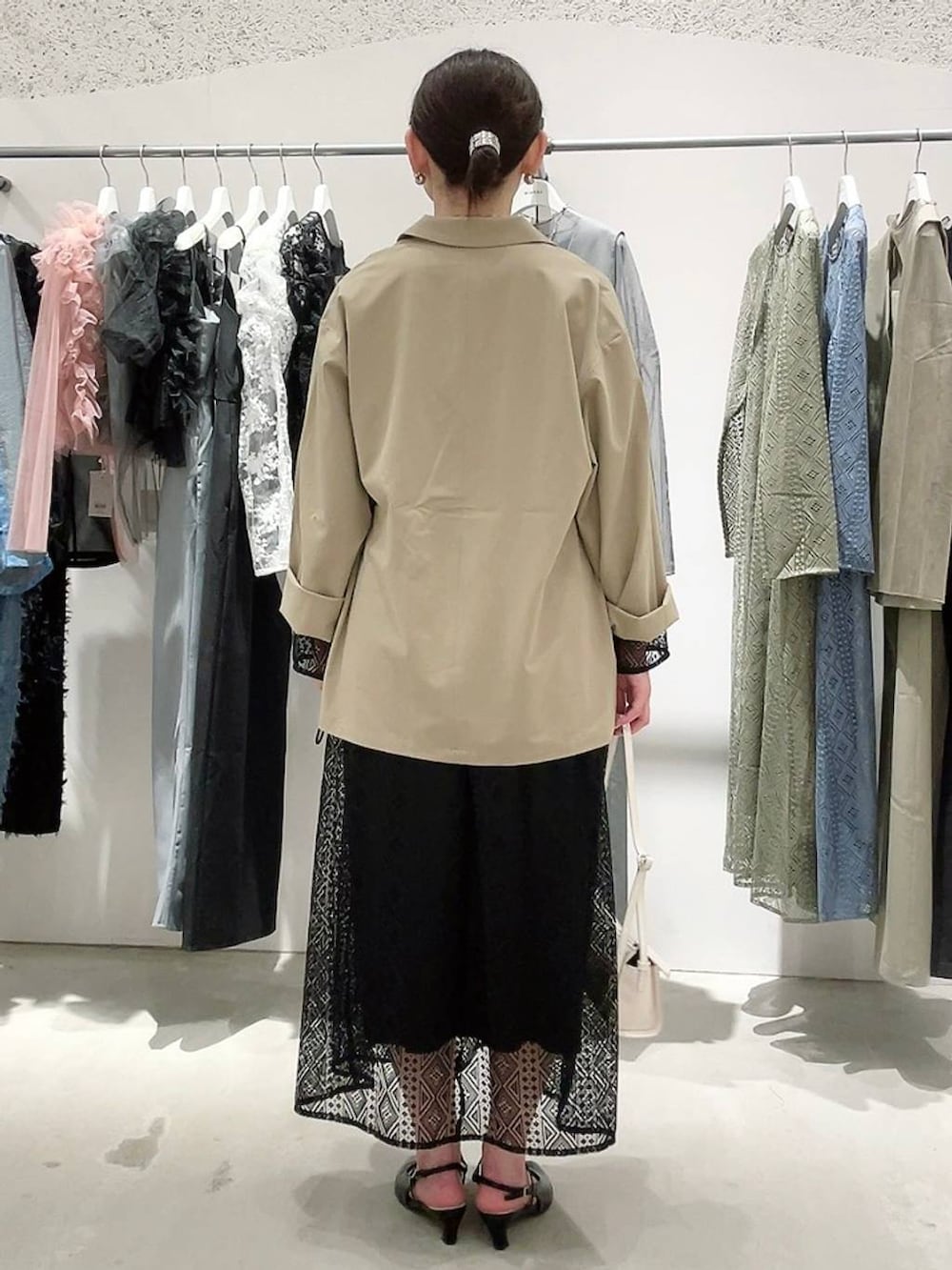 ベージュ系のテーラードジャケット、ブラック系のドレス、ゴールド系のネックレスを着用したレディースの春コーディネートの4枚目の写真